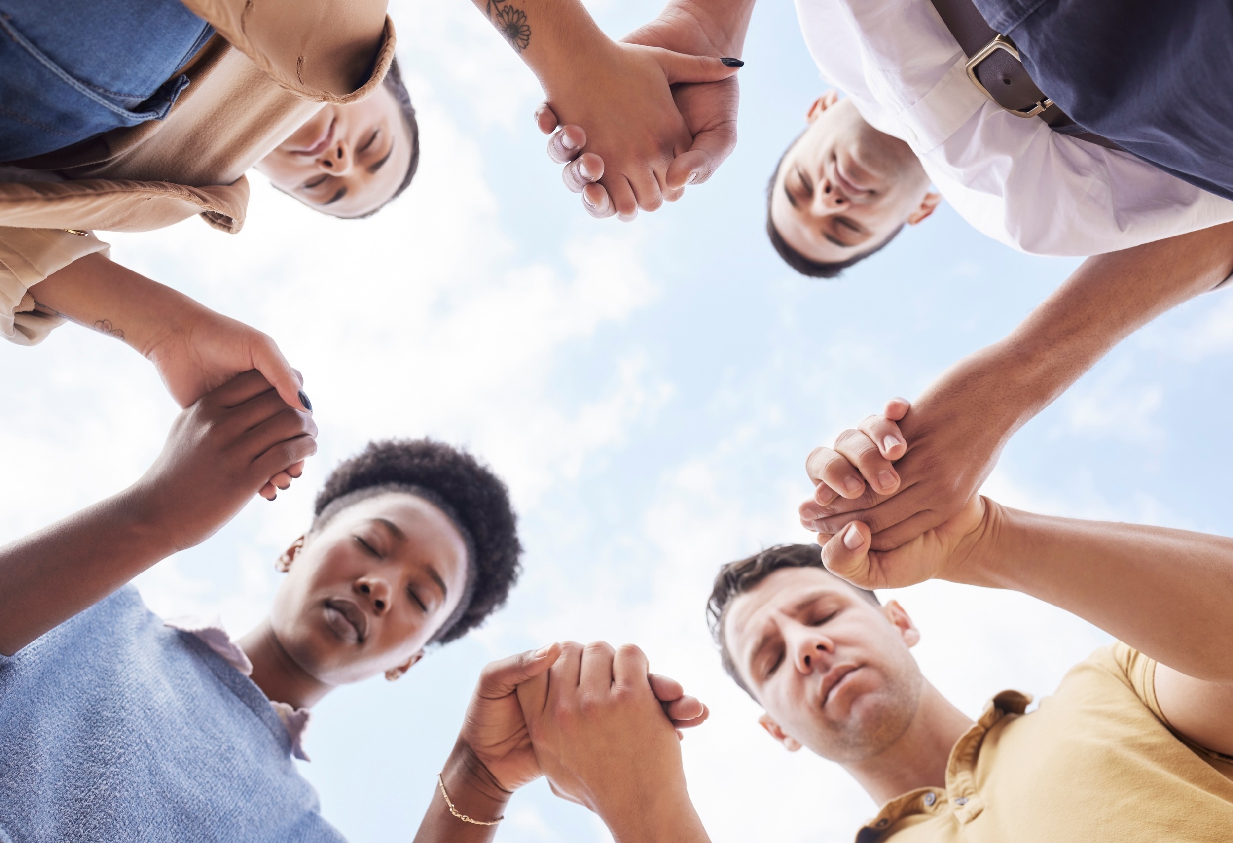 Holding hands, prayer circle and business people with support, faith and diversity in low angle by sky. Men, woman and praying for worship, gratitude and progress of business with solidarity at job.
