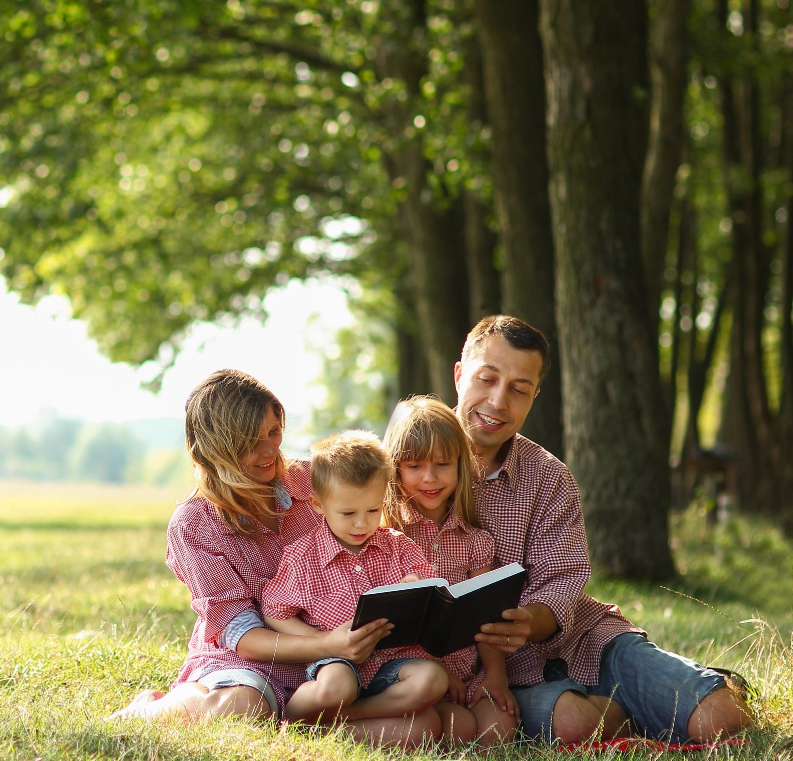 A Young family reading the Bible in nature.